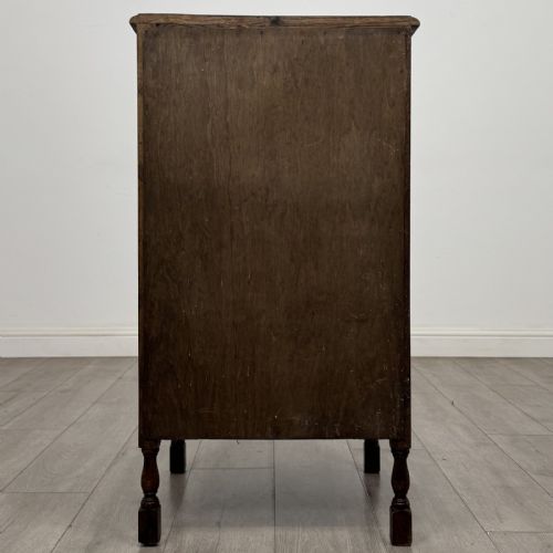 fig 4. A dark brown oak record cabinet featuring a single panelled door with a brass knob and turned legs.