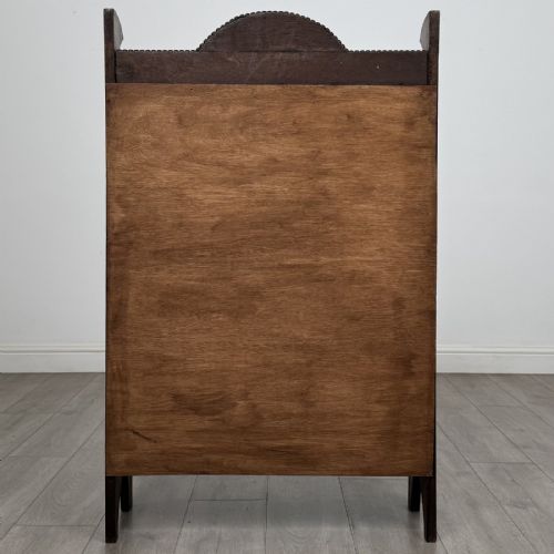 fig 5. An Arts and Crafts dark oak open bookcase featuring three shelves, a light blue painted back panel, and a carved cresting gallery.