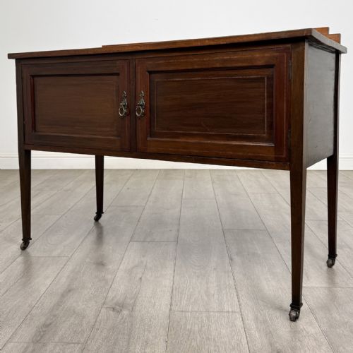 fig 1. An Edwardian mahogany side cabinet featuring double panelled doors with line inlay, square tapered legs, brass drop handles, and brass castors.