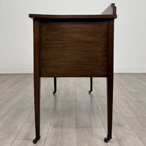 fig 2. An Edwardian mahogany side cabinet featuring double panelled doors with line inlay, square tapered legs, brass drop handles, and brass castors.