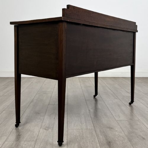 fig 3. An Edwardian mahogany side cabinet featuring double panelled doors with line inlay, square tapered legs, brass drop handles, and brass castors.