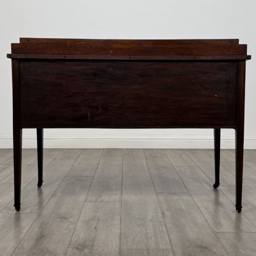 fig 4. An Edwardian mahogany side cabinet featuring double panelled doors with line inlay, square tapered legs, brass drop handles, and brass castors.
