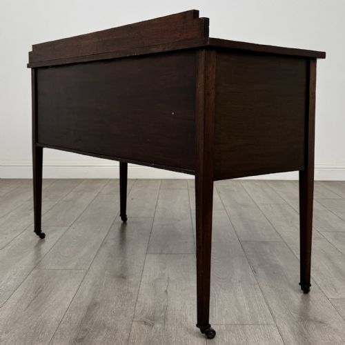 fig 5. An Edwardian mahogany side cabinet featuring double panelled doors with line inlay, square tapered legs, brass drop handles, and brass castors.