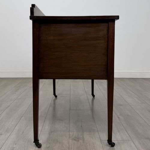 fig 6. An Edwardian mahogany side cabinet featuring double panelled doors with line inlay, square tapered legs, brass drop handles, and brass castors.