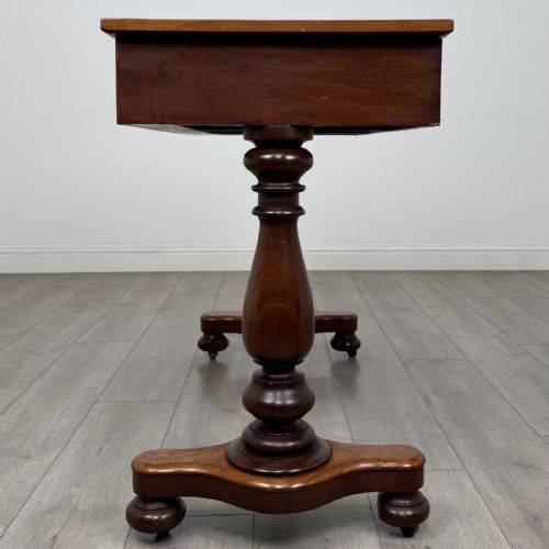 fig 2. A Victorian mahogany writing table featuring three front drawers with white porcelain knobs, set on turned baluster legs with a central stretcher bar and castors.