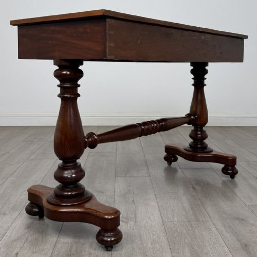 fig 3. A Victorian mahogany writing table featuring three front drawers with white porcelain knobs, set on turned baluster legs with a central stretcher bar and castors.