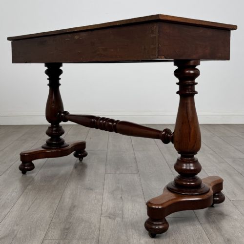fig 5. A Victorian mahogany writing table featuring three front drawers with white porcelain knobs, set on turned baluster legs with a central stretcher bar and castors.
