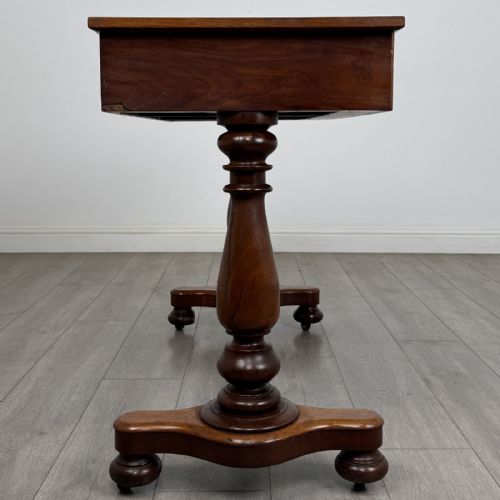 fig 6. A Victorian mahogany writing table featuring three front drawers with white porcelain knobs, set on turned baluster legs with a central stretcher bar and castors.