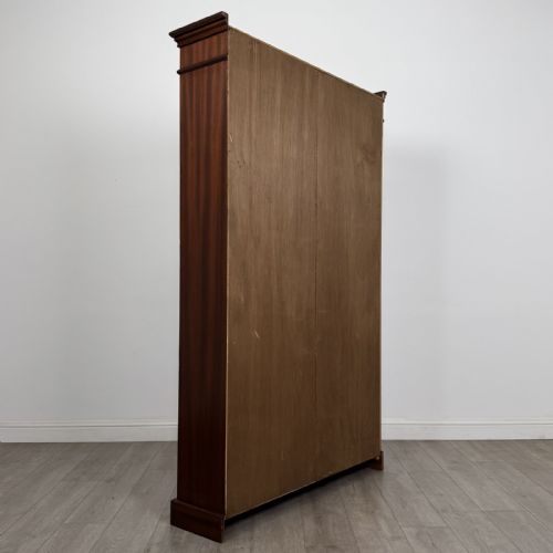 fig 3. A tall, dark mahogany double-bay open bookcase featuring multiple shelves, a moulded cornice top, and a solid plinth base.