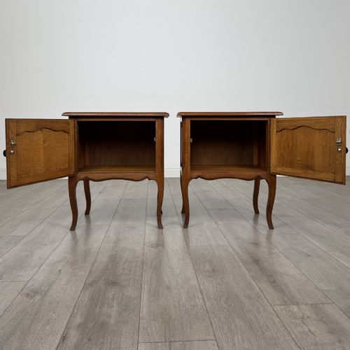 fig 1. A matching pair of vintage warm oak French style bedside cabinets featuring cabriole legs, single panelled doors, and metal knobs.