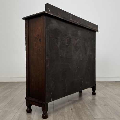 fig 3. A dark oak Jacobean style display cabinet featuring twin leaded glass doors, central carved bosses, internal shelving, and turned feet.