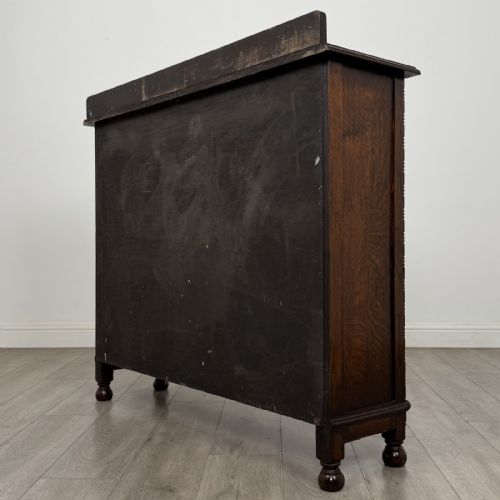 fig 5. A dark oak Jacobean style display cabinet featuring twin leaded glass doors, central carved bosses, internal shelving, and turned feet.