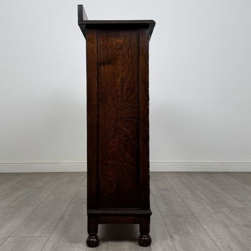 fig 6. A dark oak Jacobean style display cabinet featuring twin leaded glass doors, central carved bosses, internal shelving, and turned feet.