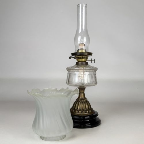 fig 3. A Victorian brass oil lamp with a black stepped base, a cut glass reservoir, an exposed glass chimney, and a swirled frosted glass shade with a ruffled rim.