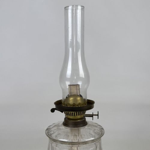 fig 4. A Victorian brass oil lamp with a black stepped base, a cut glass reservoir, an exposed glass chimney, and a swirled frosted glass shade with a ruffled rim.