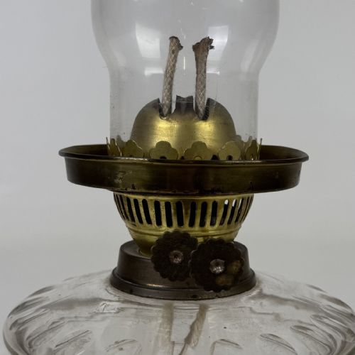 fig 5. A Victorian brass oil lamp with a black stepped base, a cut glass reservoir, an exposed glass chimney, and a swirled frosted glass shade with a ruffled rim.
