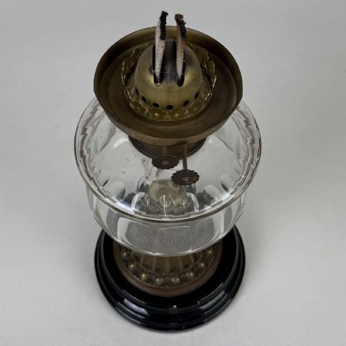 fig 6. A Victorian brass oil lamp with a black stepped base, a cut glass reservoir, an exposed glass chimney, and a swirled frosted glass shade with a ruffled rim.