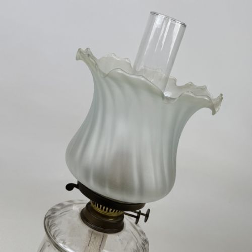 fig 7. A Victorian brass oil lamp with a black stepped base, a cut glass reservoir, an exposed glass chimney, and a swirled frosted glass shade with a ruffled rim.