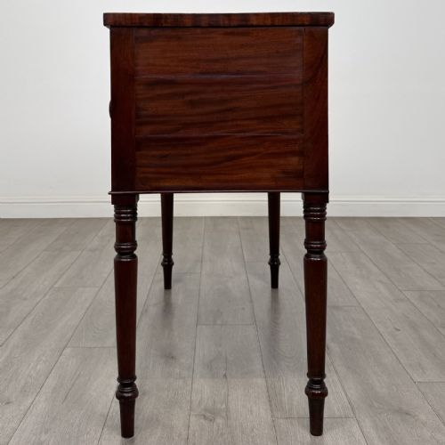 fig 2. A Regency mahogany kneehole sideboard featuring turned legs, flame mahogany drawer fronts, and fan-carved spandrel corner details.
