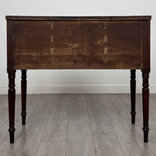 fig 4. A Regency mahogany kneehole sideboard featuring turned legs, flame mahogany drawer fronts, and fan-carved spandrel corner details.