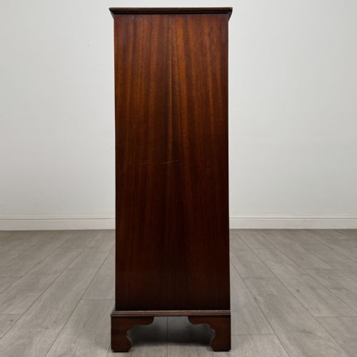 fig 2. A tall Georgian style mahogany chest of drawers featuring brass swan neck handles, a pull-out brushing slide, and bracket feet.