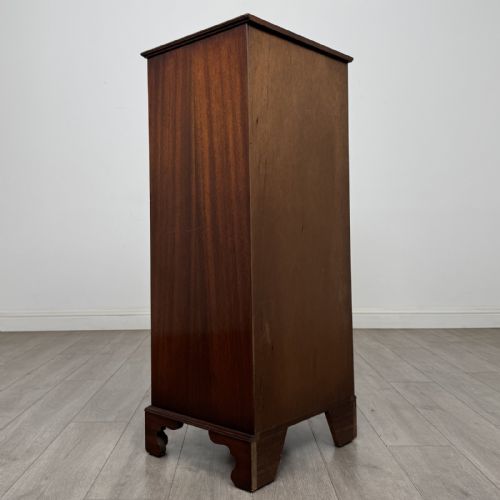 fig 3. A tall Georgian style mahogany chest of drawers featuring brass swan neck handles, a pull-out brushing slide, and bracket feet.