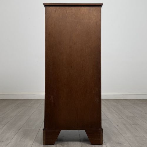 fig 4. A tall Georgian style mahogany chest of drawers featuring brass swan neck handles, a pull-out brushing slide, and bracket feet.