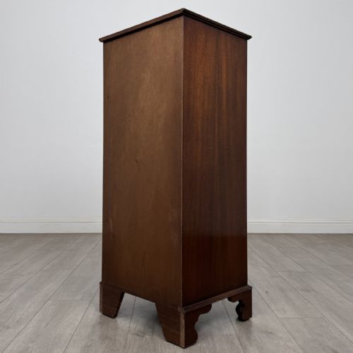 fig 5. A tall Georgian style mahogany chest of drawers featuring brass swan neck handles, a pull-out brushing slide, and bracket feet.