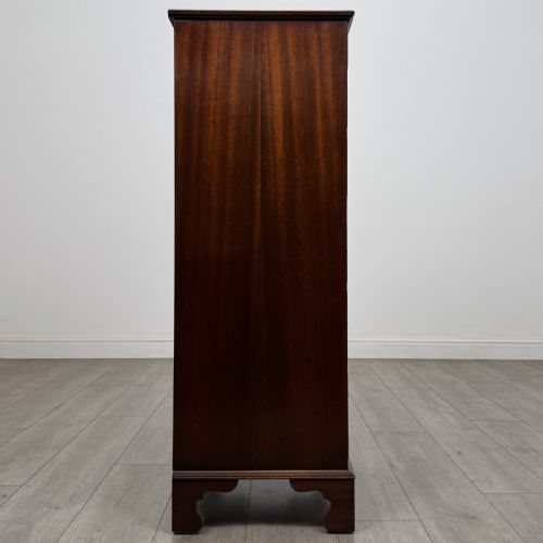 fig 6. A tall Georgian style mahogany chest of drawers featuring brass swan neck handles, a pull-out brushing slide, and bracket feet.