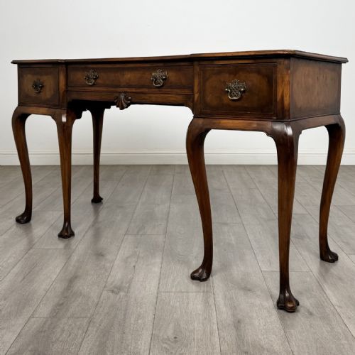fig 1. A Queen Anne style walnut writing table featuring three drawers, decorative brass handles, carved cabriole legs, and a central shell motif on the lower apron.