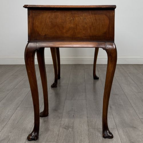 fig 2. A Queen Anne style walnut writing table featuring three drawers, decorative brass handles, carved cabriole legs, and a central shell motif on the lower apron.