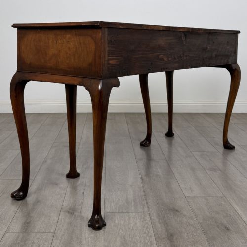 fig 3. A Queen Anne style walnut writing table featuring three drawers, decorative brass handles, carved cabriole legs, and a central shell motif on the lower apron.