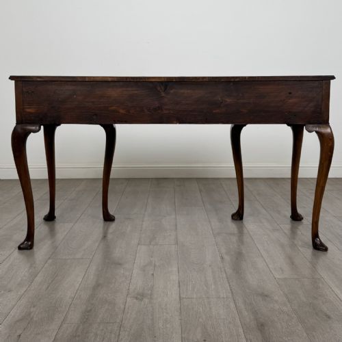 fig 4. A Queen Anne style walnut writing table featuring three drawers, decorative brass handles, carved cabriole legs, and a central shell motif on the lower apron.