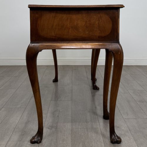 fig 6. A Queen Anne style walnut writing table featuring three drawers, decorative brass handles, carved cabriole legs, and a central shell motif on the lower apron.