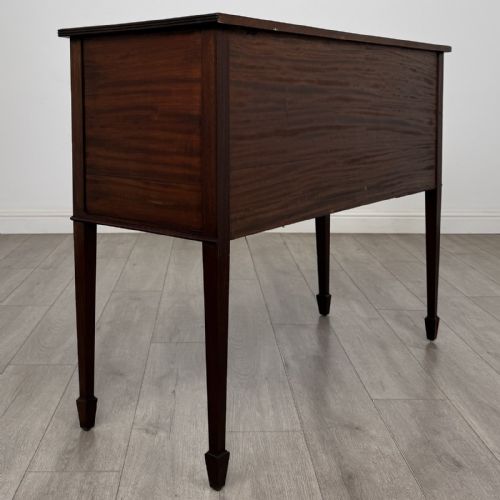 fig 3. A mahogany bowfront sideboard featuring two oval-inlaid cupboard doors flanking a central drawer, set upon four square tapered legs with spade feet.