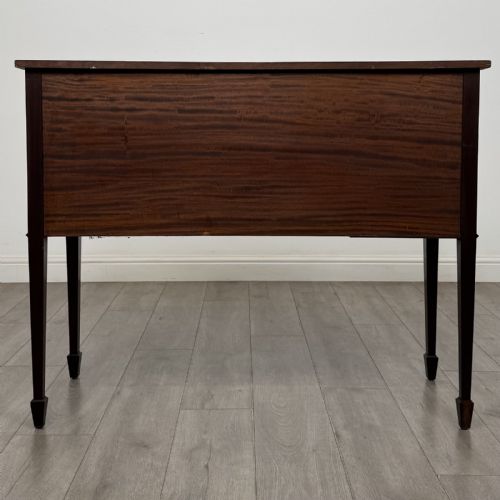 fig 4. A mahogany bowfront sideboard featuring two oval-inlaid cupboard doors flanking a central drawer, set upon four square tapered legs with spade feet.
