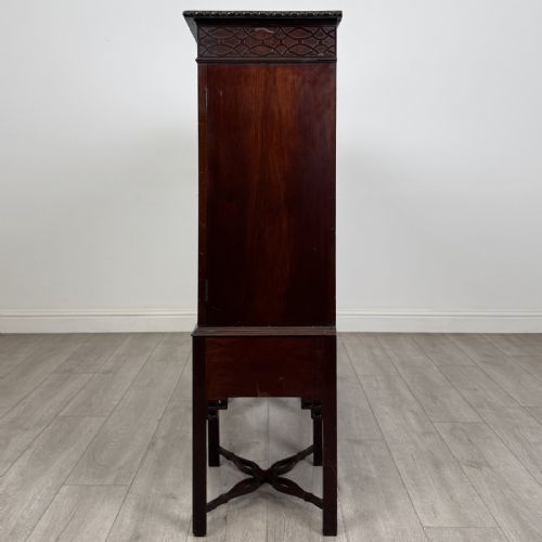 fig 2. An Edwardian dark mahogany breakfront cabinet featuring a central glazed door with geometric glazing bars flanked by two solid oval panel doors over three drawers and cross-stretched legs.