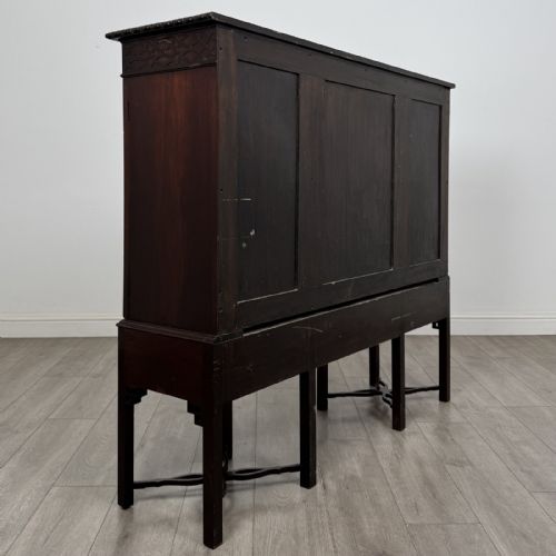 fig 3. An Edwardian dark mahogany breakfront cabinet featuring a central glazed door with geometric glazing bars flanked by two solid oval panel doors over three drawers and cross-stretched legs.
