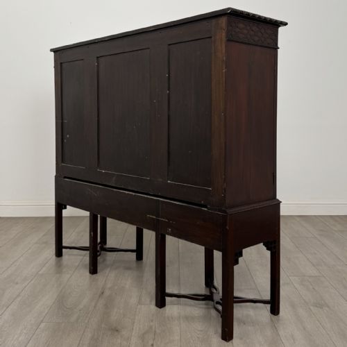 fig 5. An Edwardian dark mahogany breakfront cabinet featuring a central glazed door with geometric glazing bars flanked by two solid oval panel doors over three drawers and cross-stretched legs.
