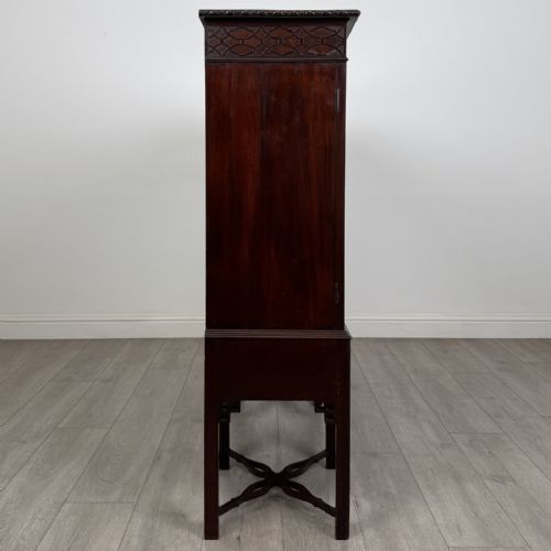 fig 6. An Edwardian dark mahogany breakfront cabinet featuring a central glazed door with geometric glazing bars flanked by two solid oval panel doors over three drawers and cross-stretched legs.