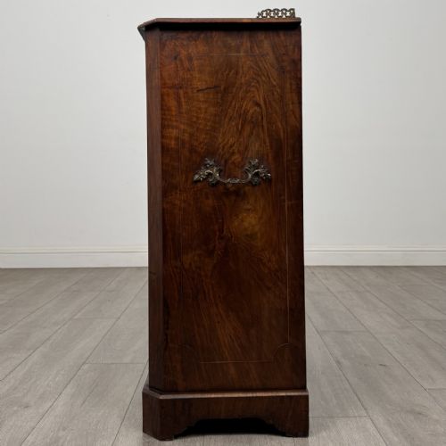 fig 2. A Victorian burr walnut music cabinet featuring a single glazed door revealing internal shelves with gilt-embossed text labels.