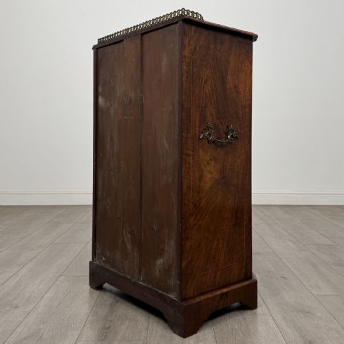 fig 5. A Victorian burr walnut music cabinet featuring a single glazed door revealing internal shelves with gilt-embossed text labels.