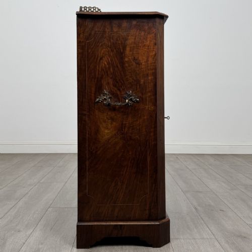 fig 6. A Victorian burr walnut music cabinet featuring a single glazed door revealing internal shelves with gilt-embossed text labels.