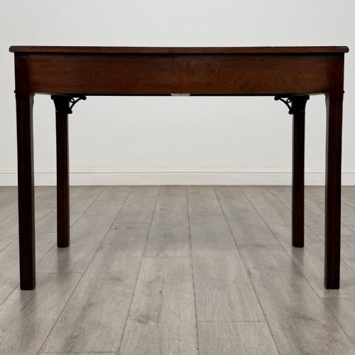 fig 4. A dark mahogany Chippendale style writing desk featuring two drawers with brass handles, straight fluted legs, and corner fretwork brackets.