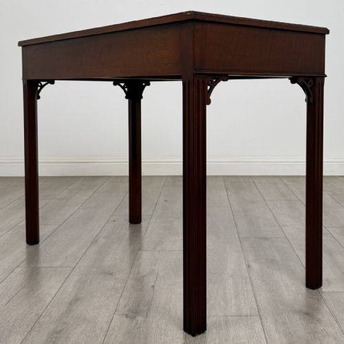 fig 5. A dark mahogany Chippendale style writing desk featuring two drawers with brass handles, straight fluted legs, and corner fretwork brackets.
