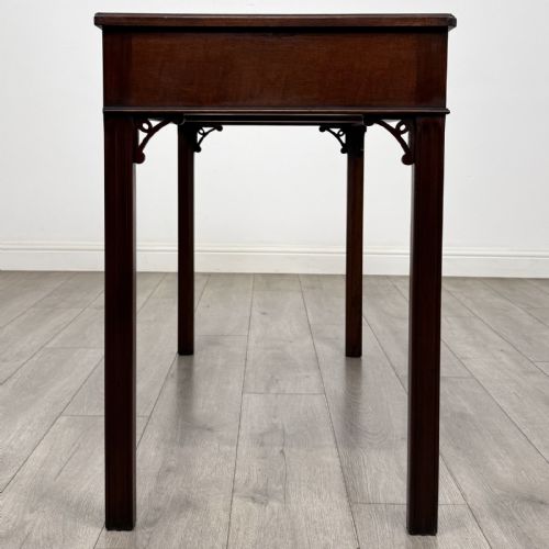 fig 6. A dark mahogany Chippendale style writing desk featuring two drawers with brass handles, straight fluted legs, and corner fretwork brackets.