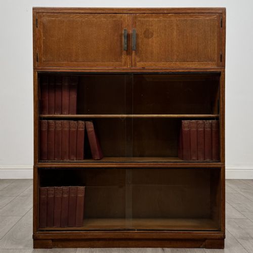 fig 1. A 20th-century oak stacking bookcase featuring a double-door wooden top cabinet above two tiered sliding glass door compartments.