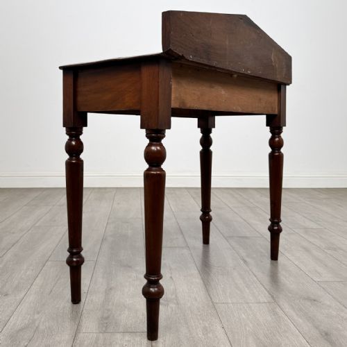 fig 3. A dark mahogany Victorian side table with turned legs and a low pediment gallery back.