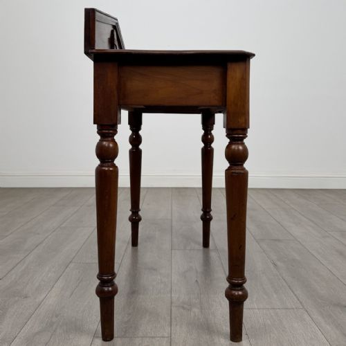 fig 6. A dark mahogany Victorian side table with turned legs and a low pediment gallery back.