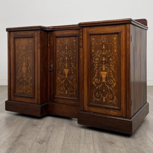 fig 1. A dark rosewood Victorian breakfront sideboard with three cupboard doors featuring intricate satinwood urn and scroll marquetry inlays.